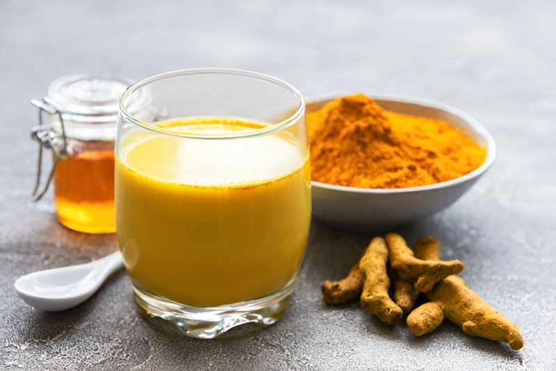 vaso de leche dorada con miel y curcuma