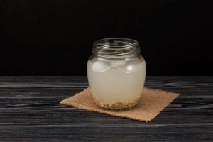 Botella de rejuvelac de trigo germinado sobre mesa de madera